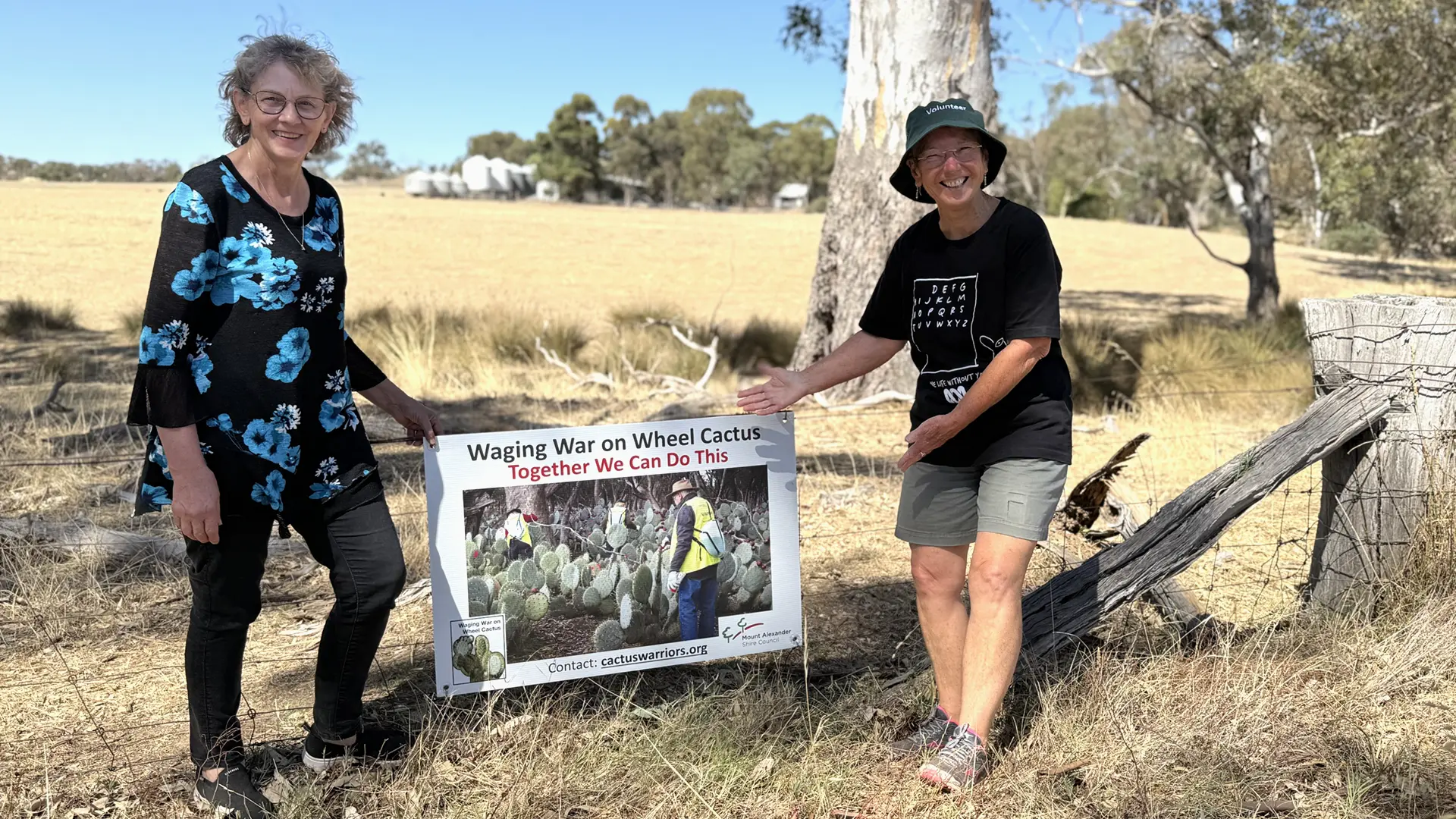 Helen Evans left and Lee Mead securing a new Wheel Cactus Farm Fence Sign.